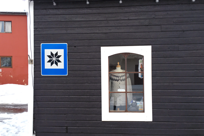 An Icelandic Lopapeysa in a shop window in Skagafjörður - the road sign is a countrywide road sign symbol used to indicate where to find handmade items. 