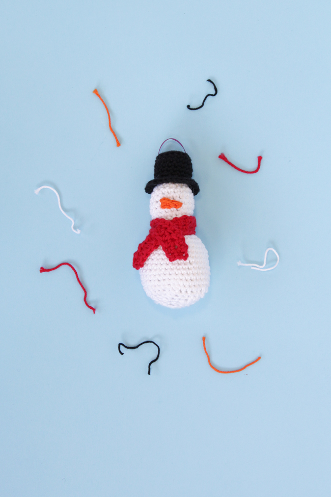 Make an adorable little snowman ornament, complete with a top hat, mini scarf, and a teensy little carrot nose. Practice your amigurumi skills with this free pattern!