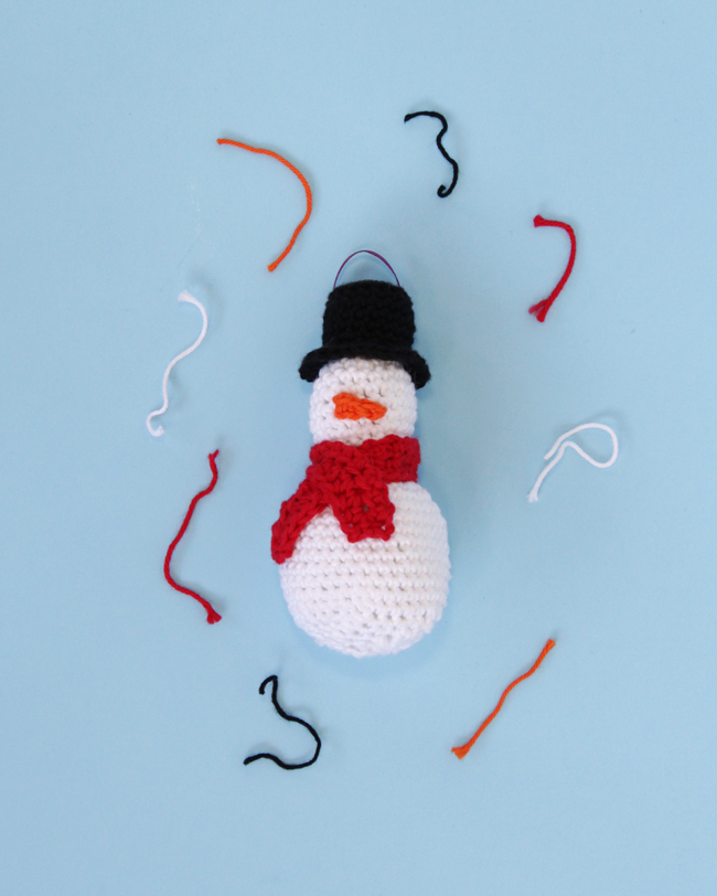 Make an adorable little snowman ornament, complete with a top hat, mini scarf, and a teensy little carrot nose. Practice your amigurumi skills with this free pattern!