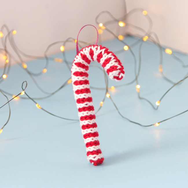 Trim your tree with this free candy cane ornament knitting pattern! Knit flat and seamed, you can quickly make this keepsake ornament with yarn scraps and pipe cleaners.