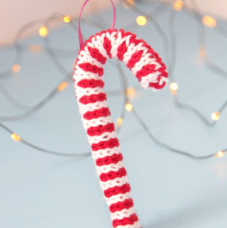 Trim your tree with this free candy cane ornament knitting pattern! Knit flat and seamed, you can quickly make this keepsake ornament with yarn scraps and pipe cleaners.