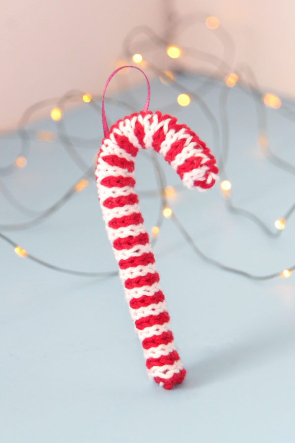 Trim your tree with this free candy cane ornament knitting pattern! Knit flat and seamed, you can quickly make this keepsake ornament with yarn scraps and pipe cleaners.