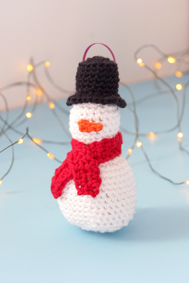 Make an adorable little snowman ornament, complete with a top hat, mini scarf, and a teensy little carrot nose. Practice your amigurumi skills with this free pattern!