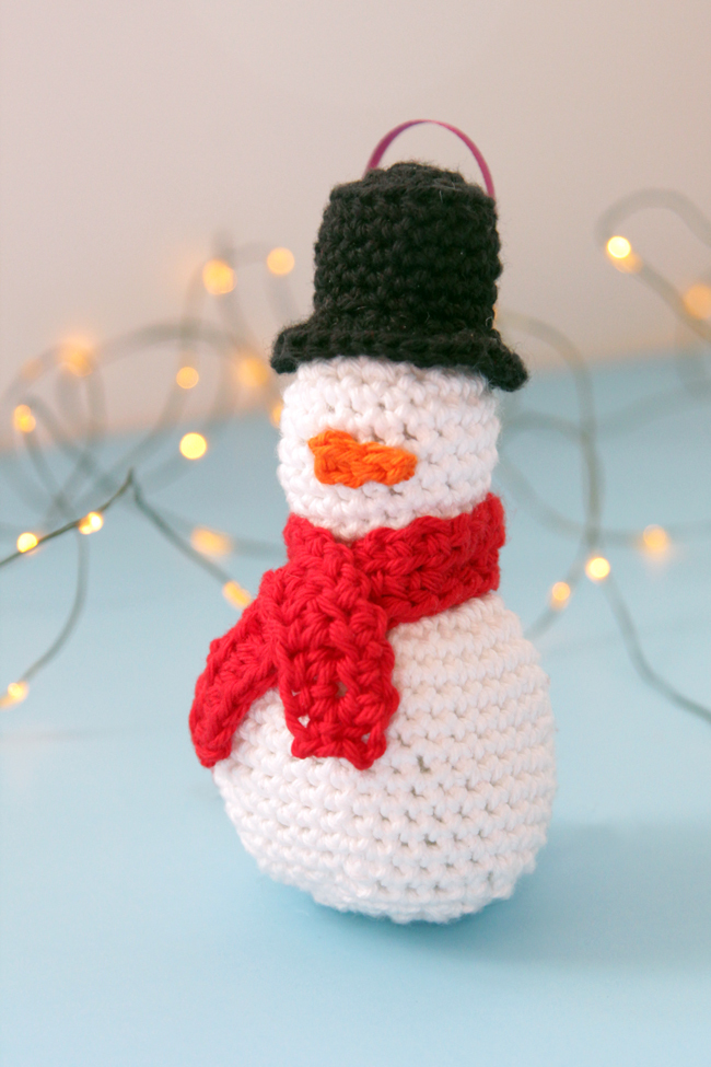 Make an adorable little snowman ornament, complete with a top hat, mini scarf, and a teensy little carrot nose. Practice your amigurumi skills with this free pattern!