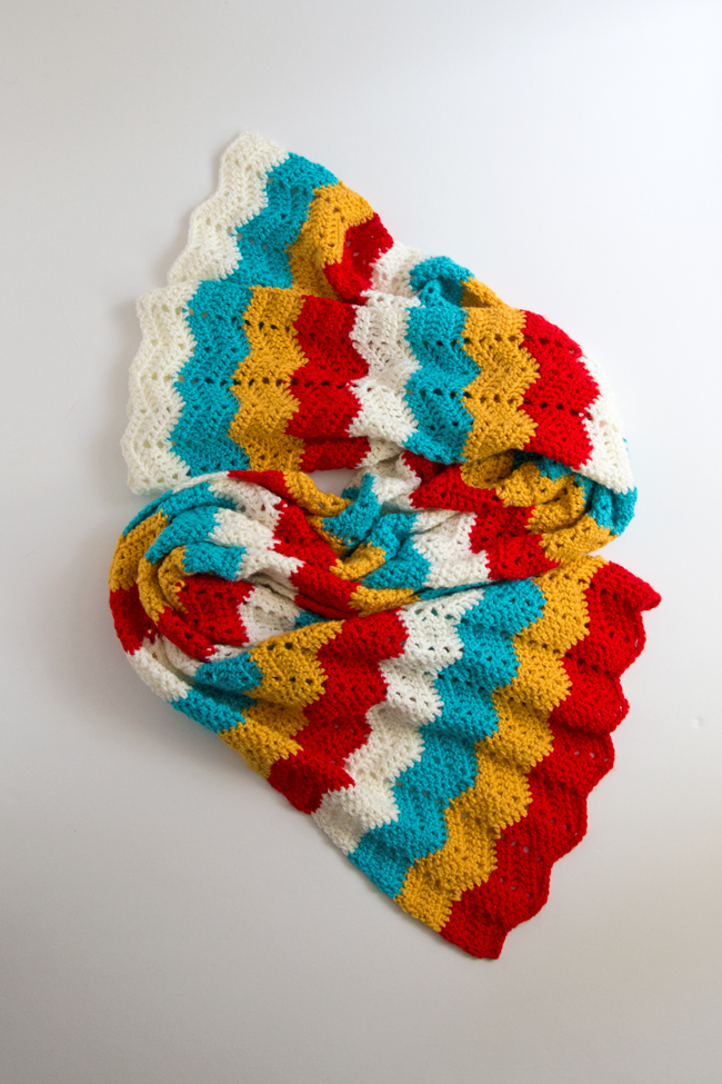 Get your hands on the free crochet pattern for the Ripple Wrap! The Ripple Wrap is a four-color take on one of the most universally-recognized crochet stitches: the ripple stitch. Seen in afghan patterns in grandmothers' houses everywhere, the ripple stitch creates a fun zig zag pattern that opens up tons of possibilities for color combos.