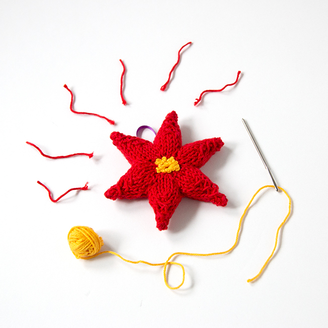Trim your tree with a hand knit ornament! This festive poinsettia will add a splash of color to your holiday decor. Click through for the free knitting pattern.