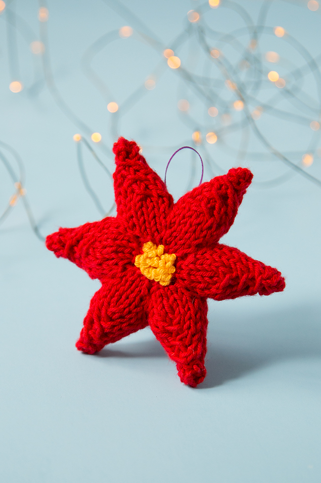 Trim your tree with a hand knit ornament! This festive poinsettia will add a splash of color to your holiday decor. Click through for the free knitting pattern.