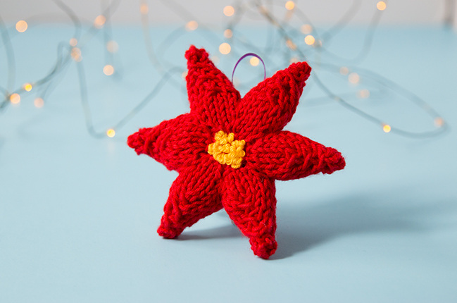 Trim your tree with a hand knit ornament! This festive poinsettia will add a splash of color to your holiday decor. Click through for the free knitting pattern.