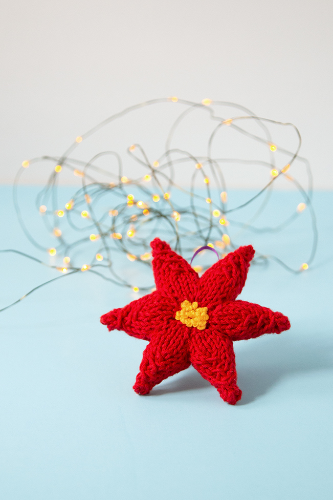 Trim your tree with a hand knit ornament! This festive poinsettia will add a splash of color to your holiday decor. Click through for the free knitting pattern.