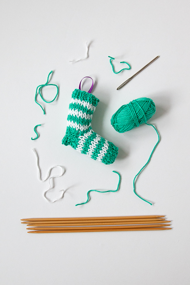 A tiny knit stocking is the most adorable way to trim your tree! Get the free knitting pattern for this striped stocking. #christmasornament #stockingornament #freeknittingpattern