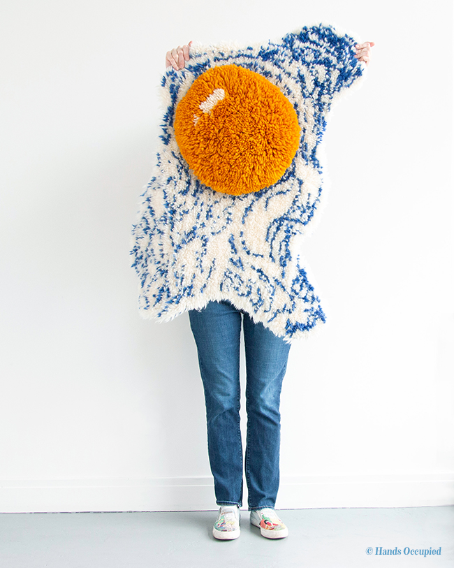 Artist Heidi Gustad models her Fried Egg Wall Hanging, the cover project from her first book, Latch Hook: 12 Projects for the Modern Maker