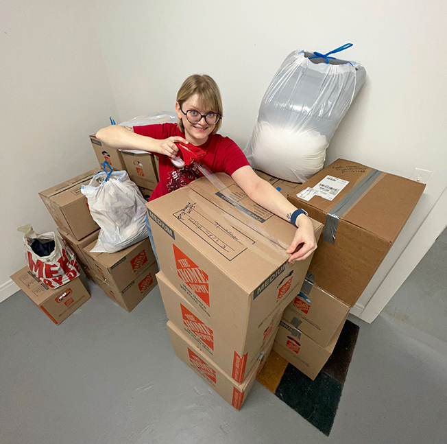 A blond woman packing several boxes.